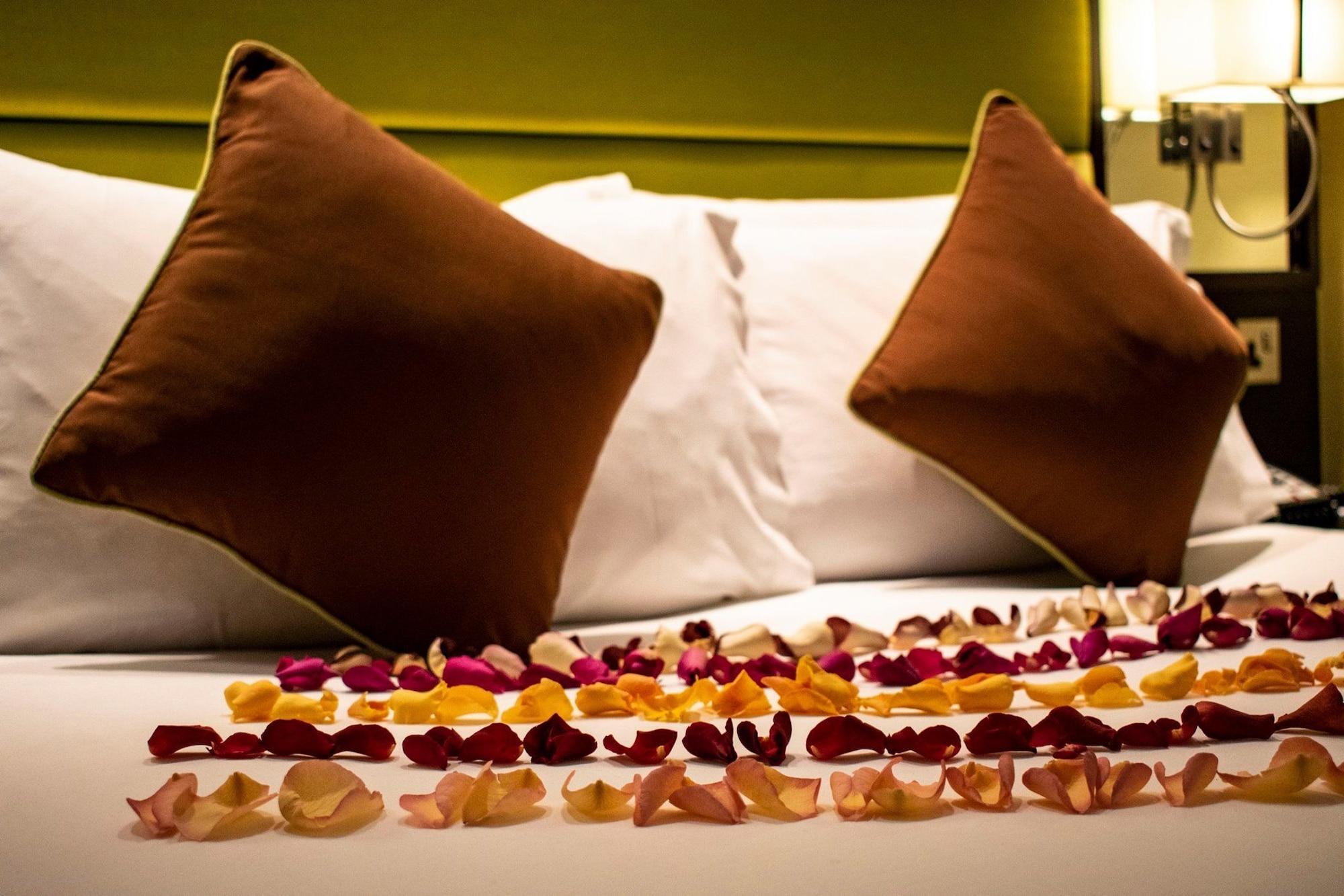 Montcalm Brewery Townhouse Hotel London Bagian luar foto The photo shows a neatly arranged bed with two white pillows and brown decorative cushions. Scattered across the bed is a decorative display of flower petals in various colors, including pink, yellow, and orange, creating a romantic or tranquil ambia