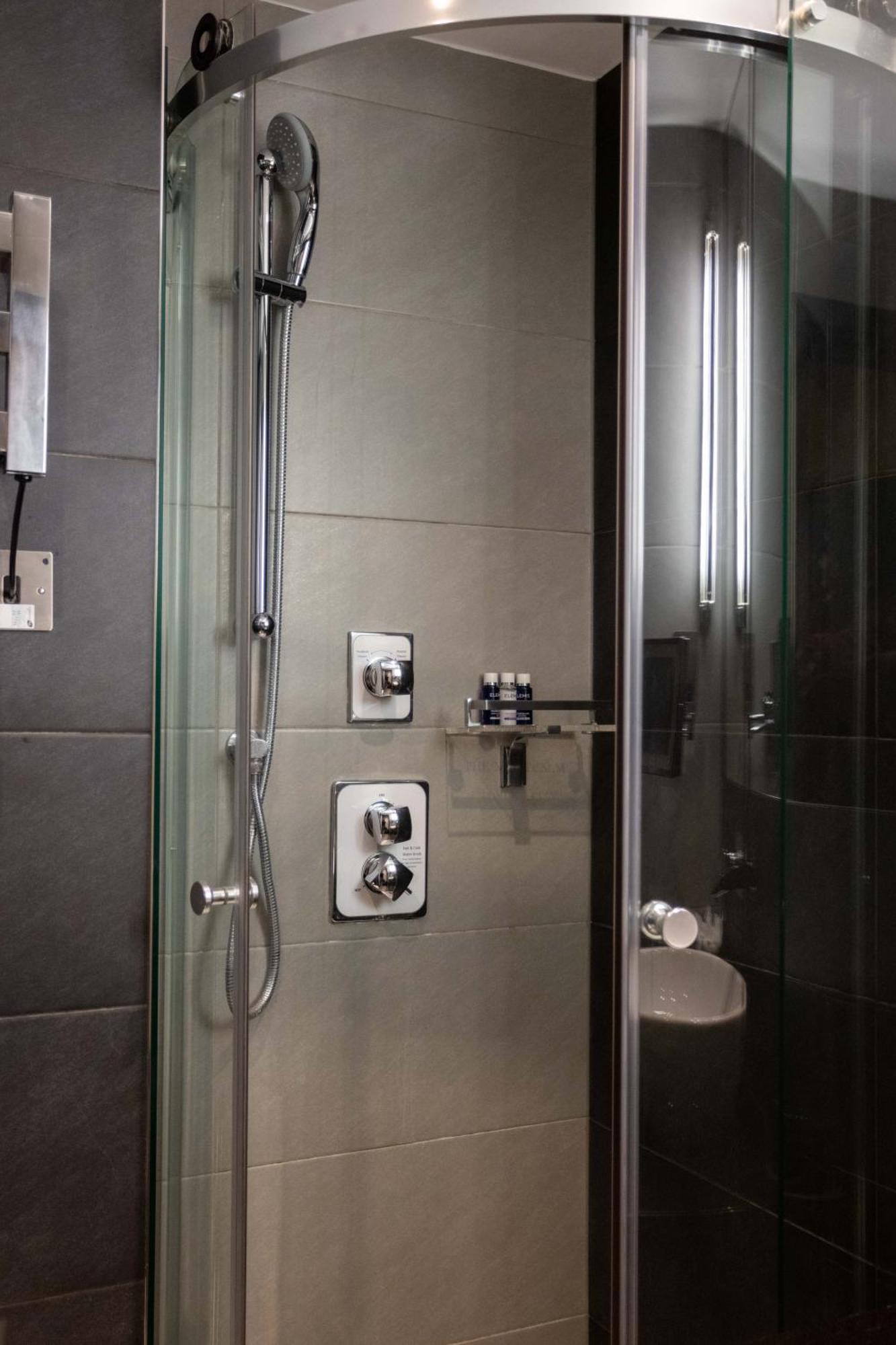 Montcalm Brewery Townhouse Hotel London Bagian luar foto The photo shows a modern shower area. It features glass panels and tiled walls in a neutral color palette, creating a sleek and contemporary look. There are two main control panels for adjusting the water temperature and pressure, with various knobs 