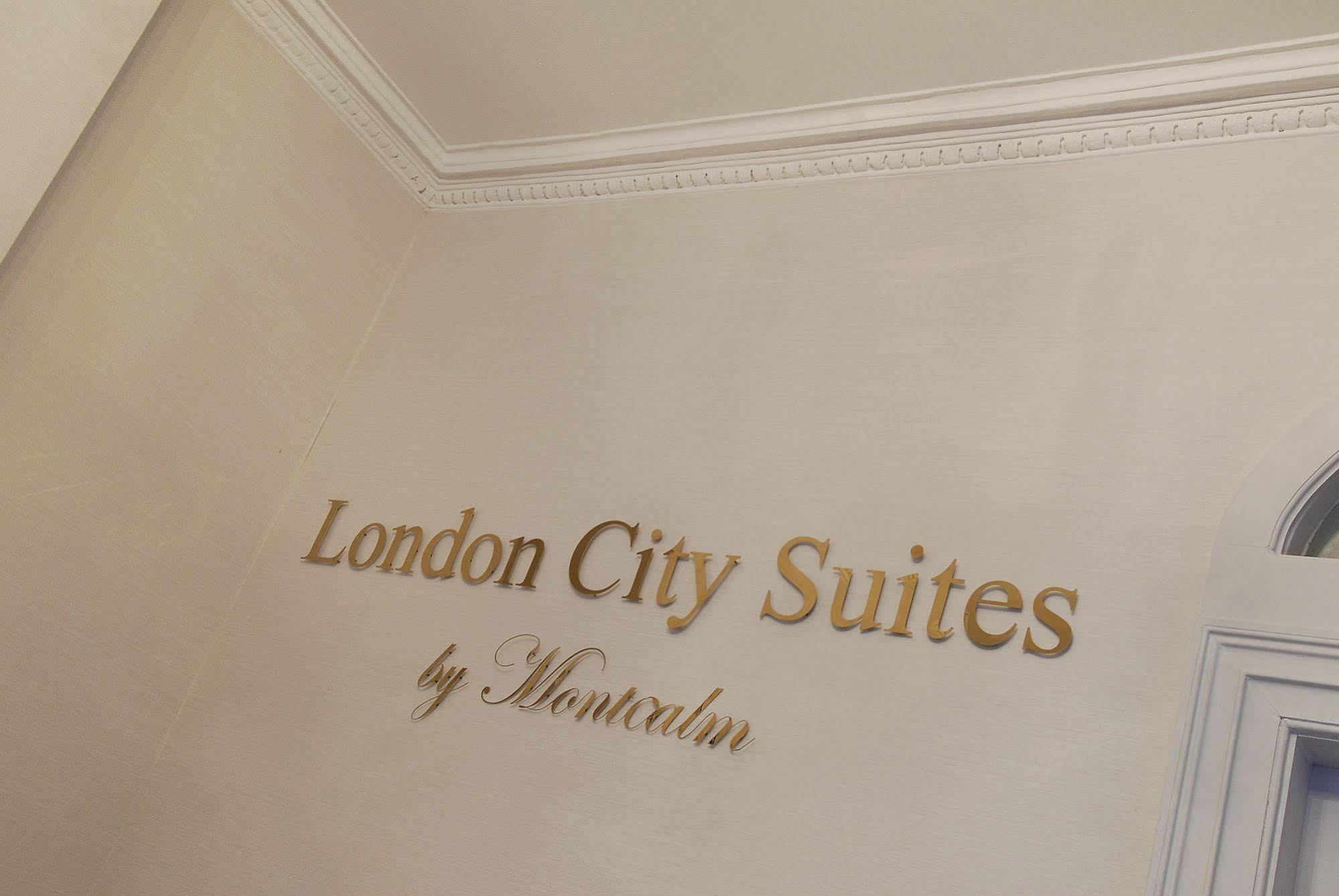 Montcalm Brewery Townhouse Hotel London Bagian luar foto The photo shows a wall display featuring the text "London City Suites" in a bold, gold-colored font. Below that, the words "by Montcalm" are written in a smaller, elegant style. The background appears to be a neutral-colored wall, possibly in a hotel