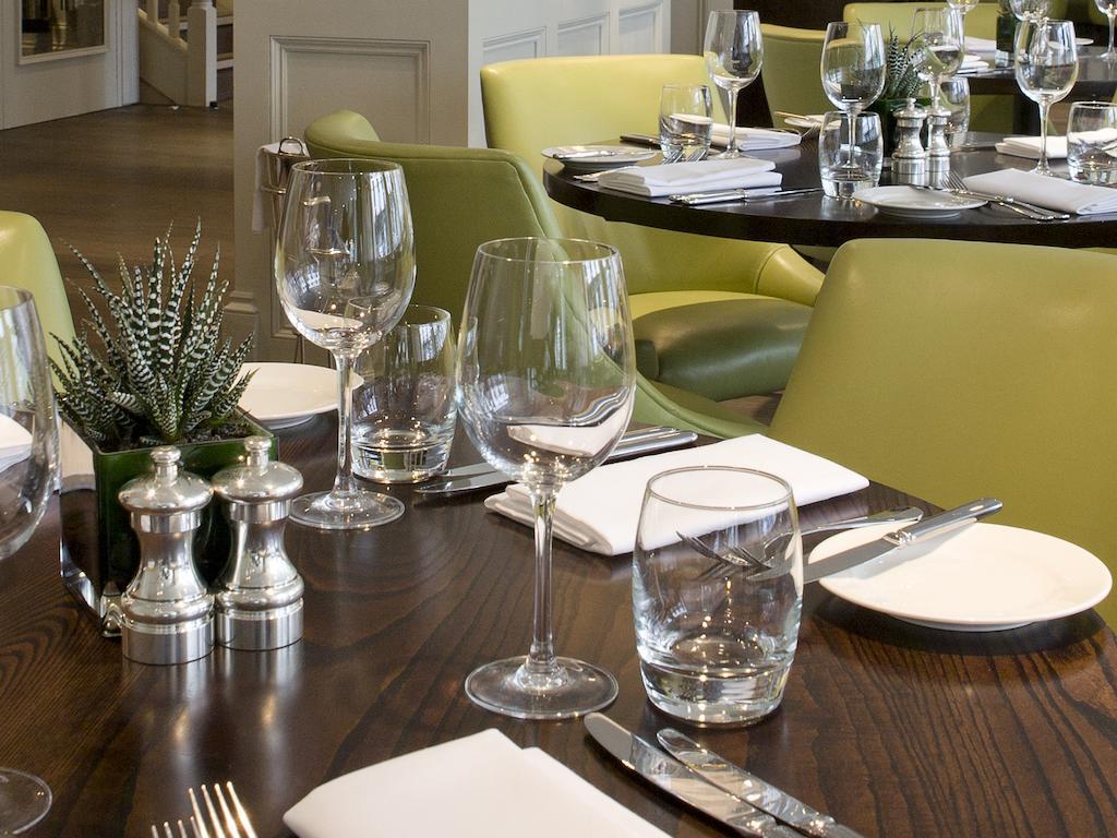Montcalm Brewery Townhouse Hotel London Bagian luar foto The photo shows a dining setup in a restaurant. There are tables with a polished wooden surface and elegant place settings. Each setting includes multiple wine glasses and water glasses, neatly arranged with folded napkins. 

In the center, there are