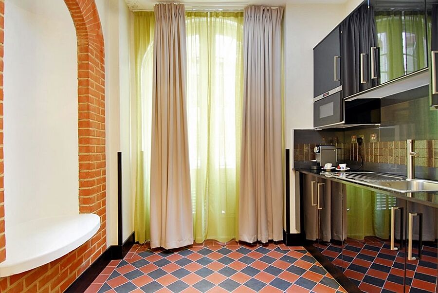 Montcalm Brewery Townhouse Hotel London Bagian luar foto The photo shows a kitchen area with modern design elements. There are large, light-colored curtains hanging from the windows, allowing natural light to filter in. The walls are partially exposed brick, giving a warm texture to the room. The flooring 