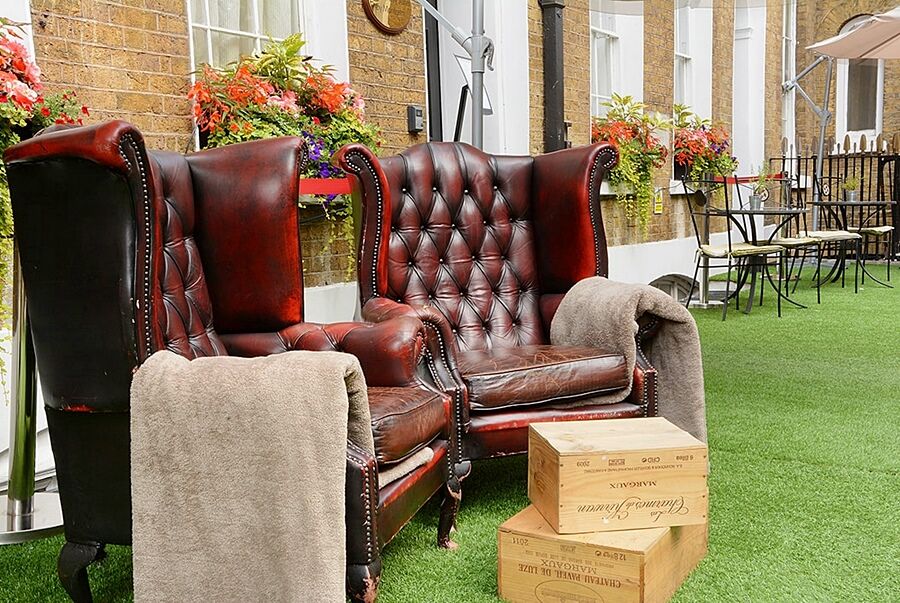 Montcalm Brewery Townhouse Hotel London Bagian luar foto The photo depicts two large, elegant armchairs with a classic design, featuring rich burgundy leather upholstery and button tufting. They are positioned in a cozy outdoor setting, with lush green artificial grass beneath them. Next to the chairs, the